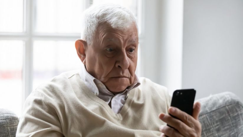 A man sitting in a chair looking at a smartphone